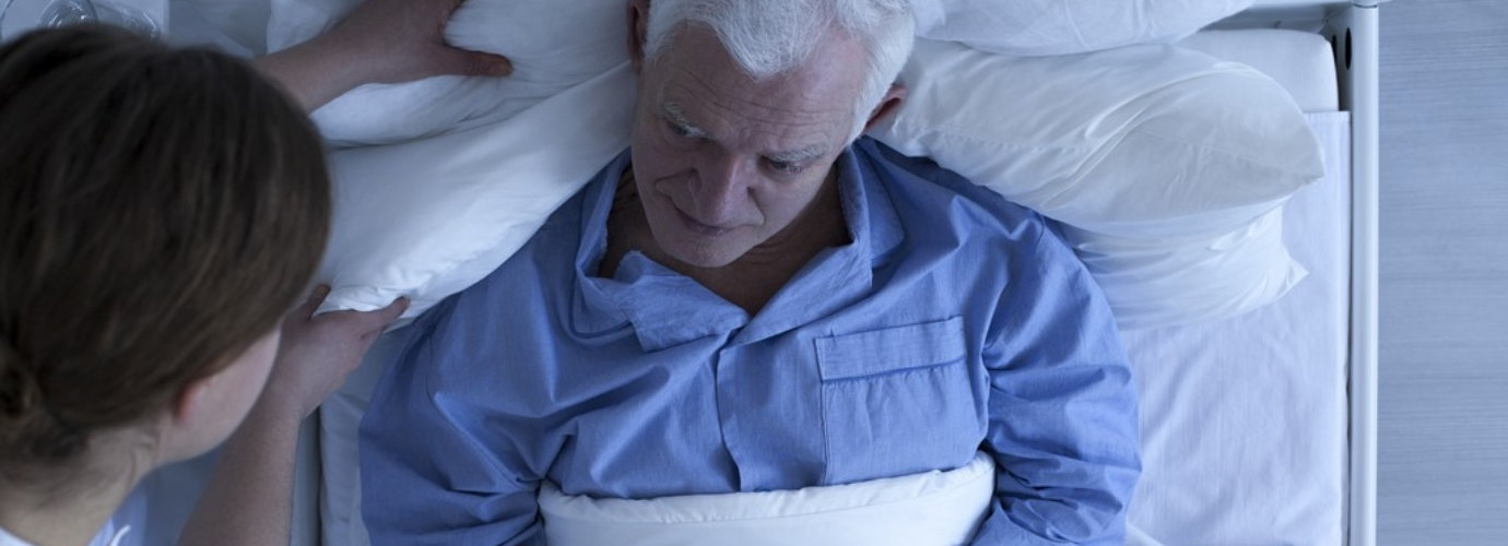 caregiver assisting senior man in bed
